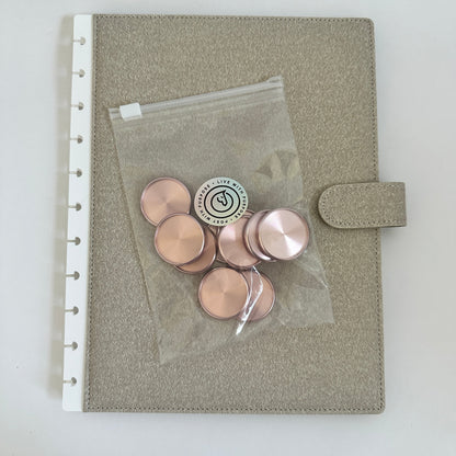 Gray pouch with pink buttons and a clear plastic bag on a white background